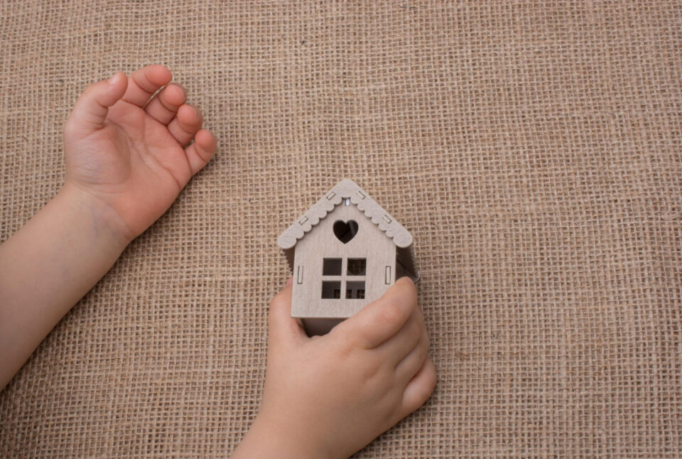 Child hand holding toy house